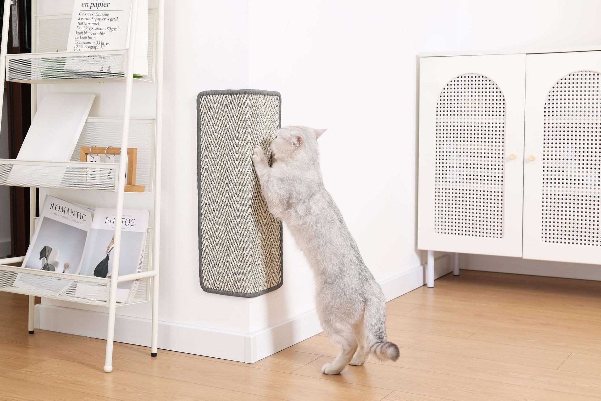 Cat using a boho-style natural sisal scratching mat attached to a wall in a modern home setting.